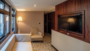 A hotel corridor with a sofa, a chair, a TV mounted on the wall, and a lamp on a side table. - Rich & Free Hotel Kaifeng (Taipei)