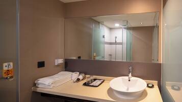 A modern bathroom with a large mirror, a sink, and a towel rack.