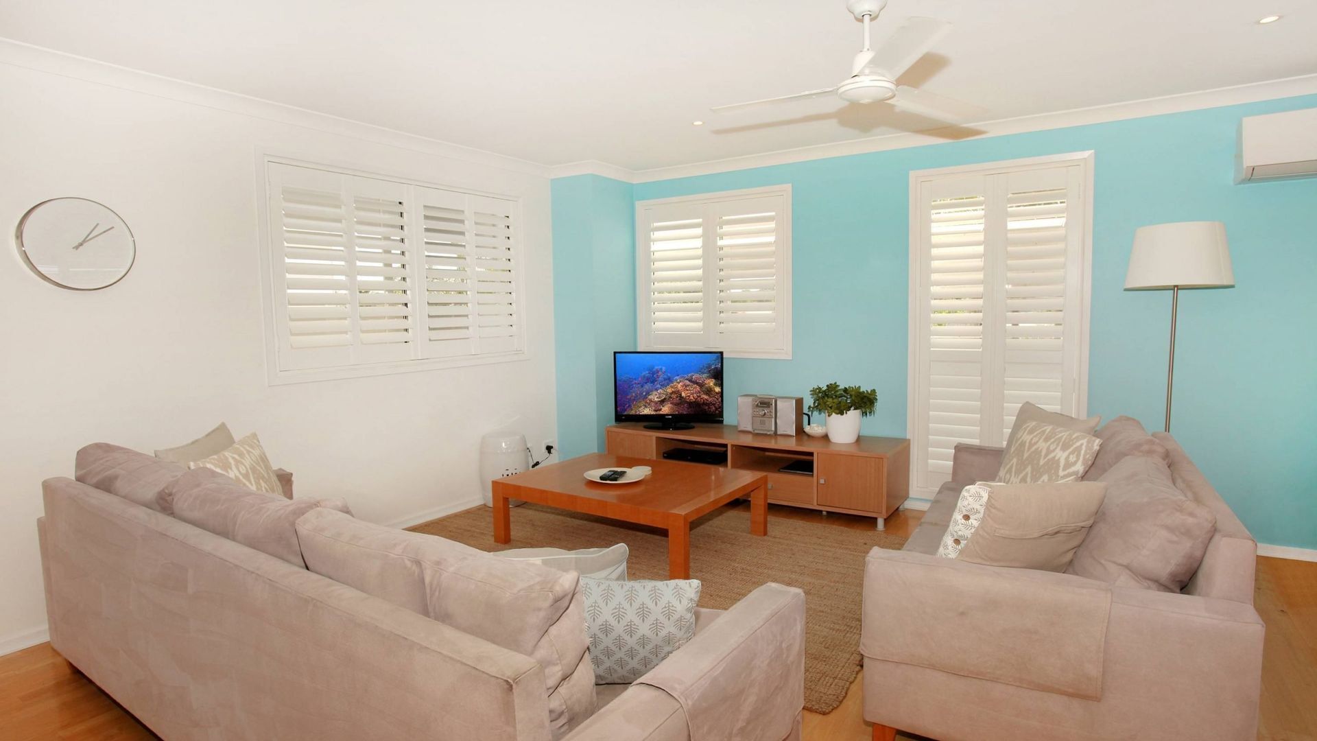 A living room with two sofas, a coffee table, a TV, and a ceiling fan.