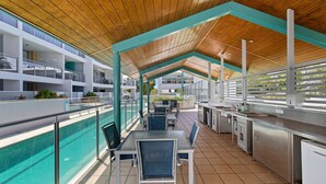 A modern outdoor dining area with a pool and a view of the building's interior. - Unit 8.12 Perry Street (Coolum Beach)
