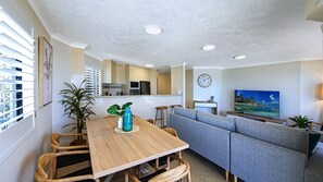 A modern living room with a sofa, TV, and a dining area with a table and chairs. - Unit 9 'The Rocks', Coolum Beach (Coolum Beach)