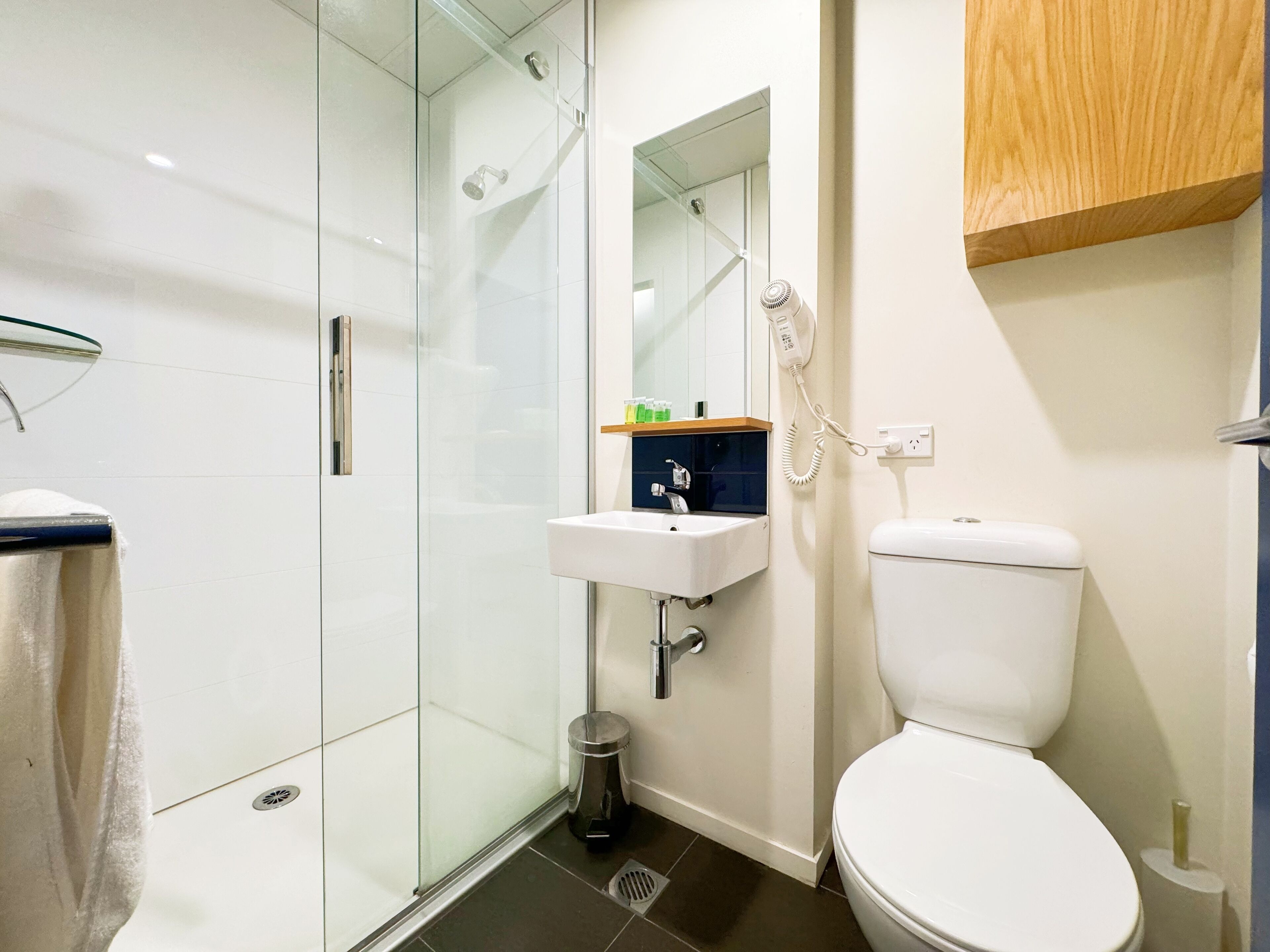 Un bagno moderno con doccia vetrata, un lavandino bianco e il water.