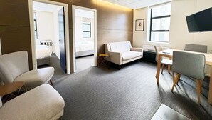 A modern hotel room with a sofa, a desk, a TV, and a bed.