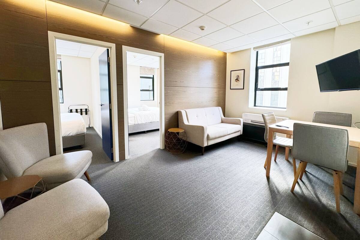 Habitación de hotel moderna con sofá, escritorio, televisor y cama.