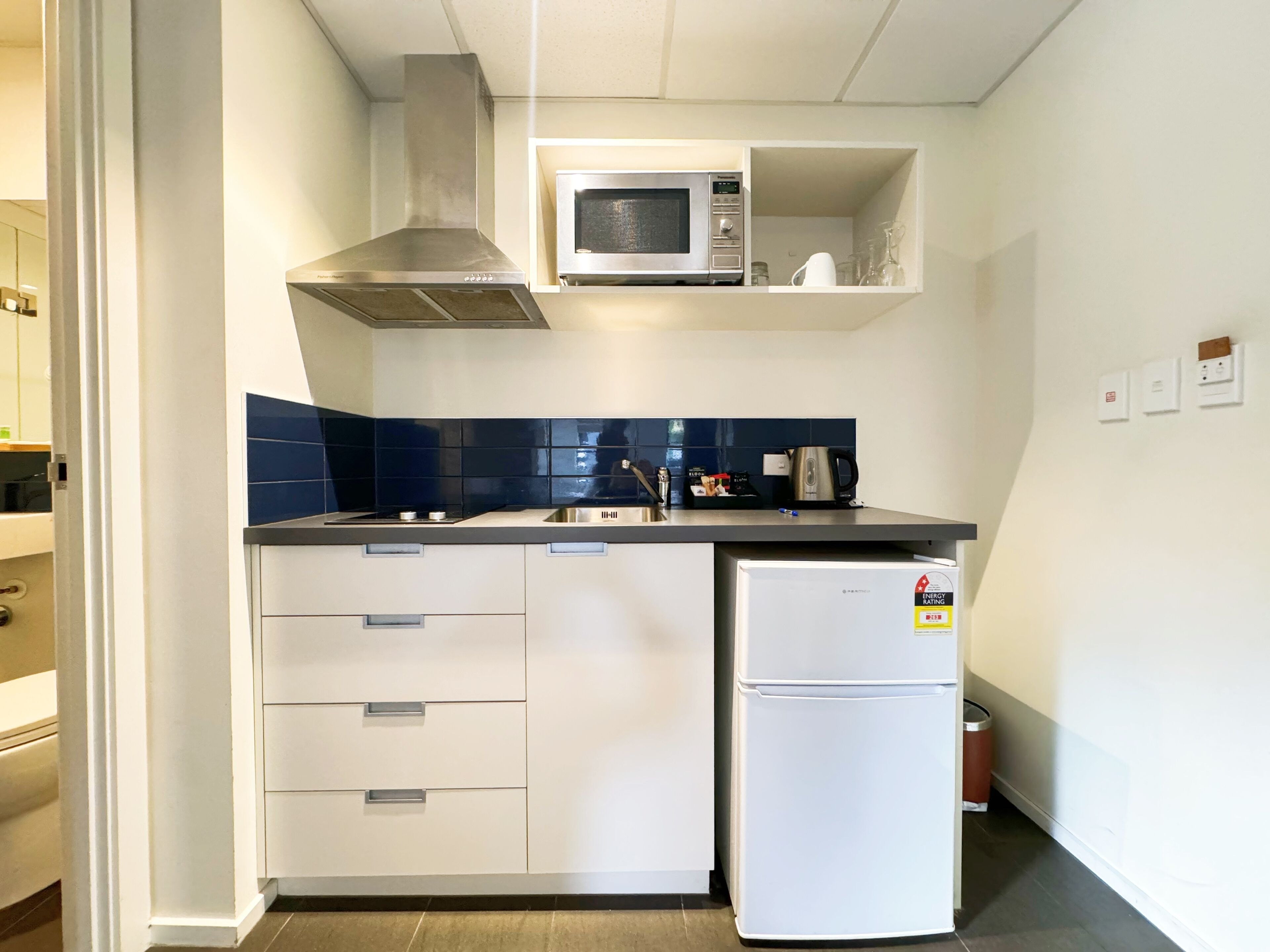 A compact kitchen with a microwave, stove, and a small refrigerator.