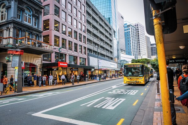 A city street with a yellow bus, pedestrians, and buildings with various storefronts. - Park Hotel Lambton Quay (Wellington)