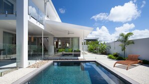 Una casa moderna amb piscina, mobiliari exterior i jardí.