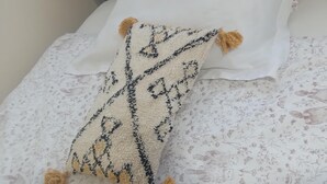 Un lit recouvert d’une couvre-lit à motifs floraux et agrémenté d’un plaid décoratif orné de glands.