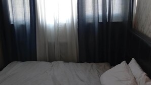 Une chambre d’hôtel avec un lit, des rideaux et un mur décoré de motifs.