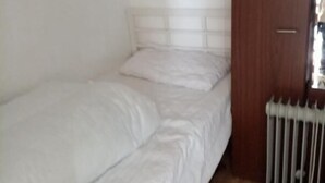 A small, single-bed room with a wooden floor, a white headboard, and a radiator. - Chalet Retreat in Mablethorpe (Mablethorpe)