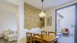A dining area with a wooden table and chairs, a brick wall, and a sign on the wall. - Mediterranean House in Badalona (Badalona)