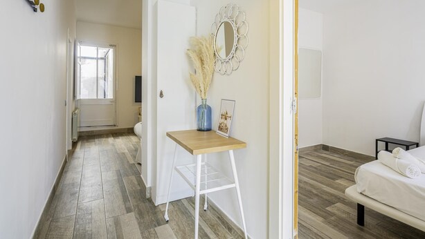 A modern, well-lit hallway with a wooden floor, a white door, and a small table with a vase and pampas grass. - Mediterranean House in Badalona (Badalona)