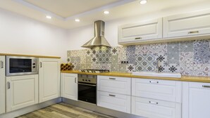 A modern kitchen with white cabinets, a stainless steel range hood, a built-in oven, and a microwave. - Mediterranean House in Badalona (Badalona)
