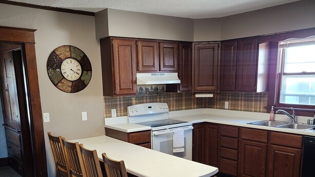 Une cuisine avec un îlot central, des meubles en bois, une cuisinière et une horloge au mur.