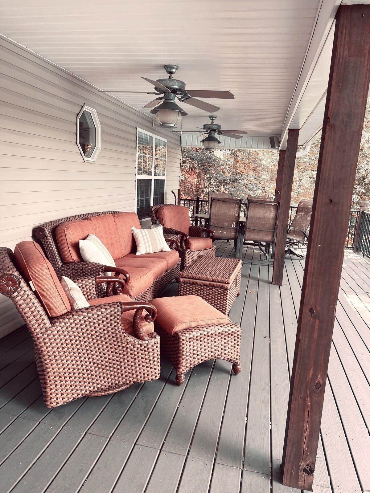 A covered porch with wicker furniture, including a sofa and chairs, and a ceiling fan.