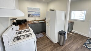 Una cocina compacta equipada con estufa a gas, refrigerador, microondas y pileta.