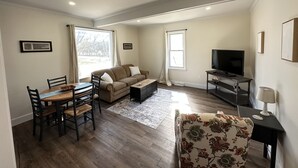 Una sala de estar con un sofá, un televisor, una mesa de comedor con sillas y una mesa de centro.