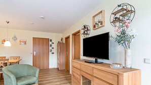 Un salon moderne doté d’un téléviseur à écran plat, de meubles en bois et d’objets décoratifs.