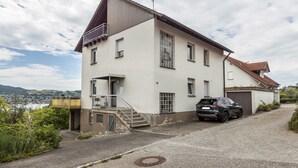Una casa a due piani con un garage, una scala che conduce all'ingresso e un'auto parcheggiata nel vialetto.