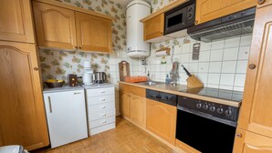 Una cucina con mobili in legno, un frigorifero bianco, un fornello e un forno a microonde.