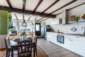 A modern kitchen with white cabinets, a built-in oven, and a dining area with a wooden table and chairs.