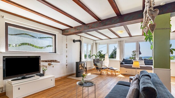 A spacious living room with a large flat-screen TV, a fireplace, a sofa, and a dining area with a table and chairs. - Apartment 'Augensteins Burgzimmer' with Private Terrace and Wi-Fi (Seelbach)