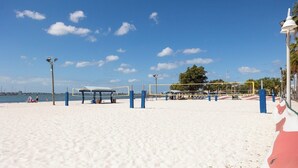 Un terrain de beach-volley avec un filet, des poteaux bleus et blancs, et un banc.