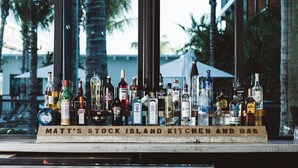 Een bar met verschillende drankflessen, tentoongesteld op een plank met de tekst 'Matt's Stock Island Kitchen and Bar'.