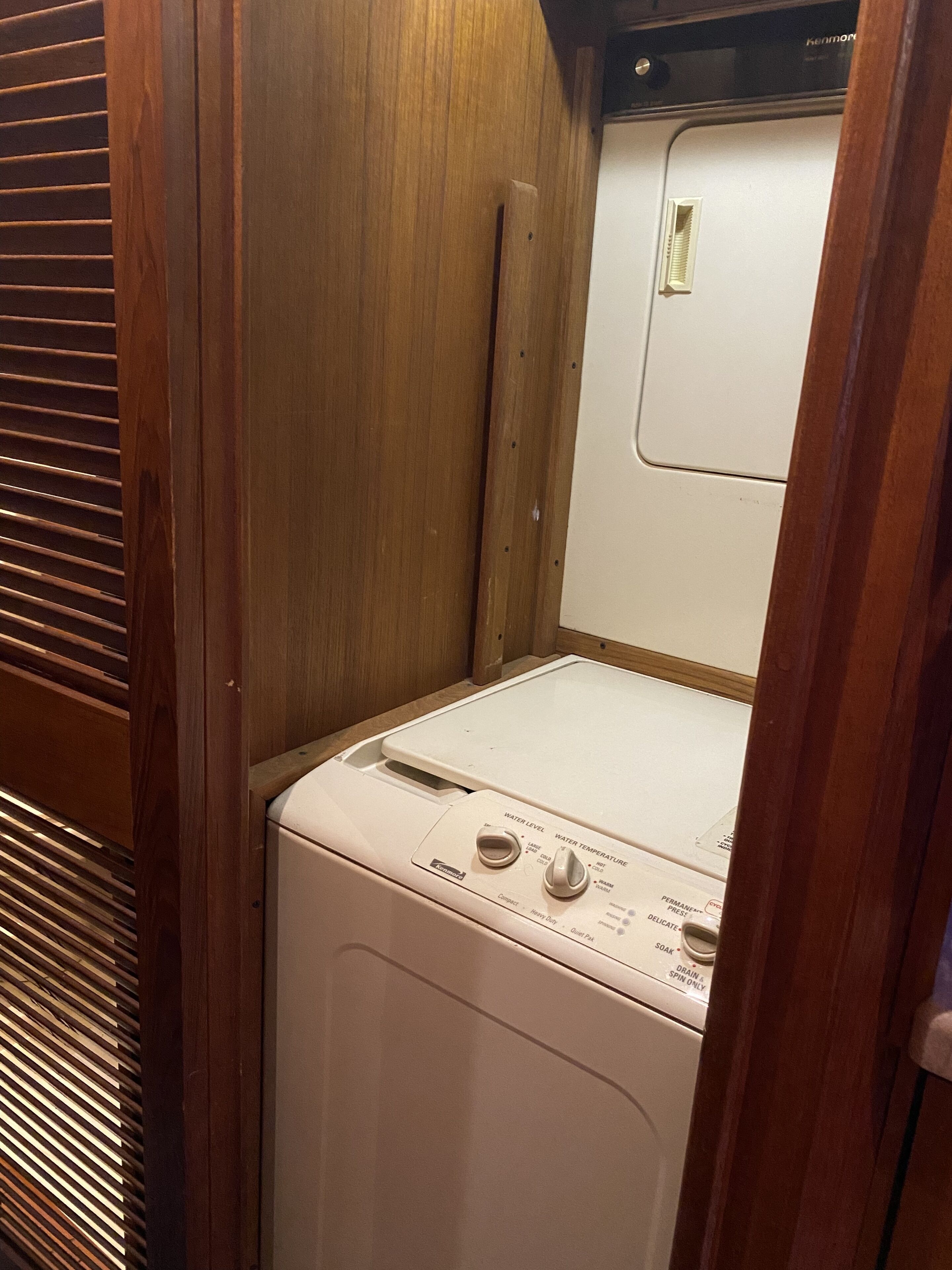 A compact, wooden-framed laundry room with a front-loading washing machine.