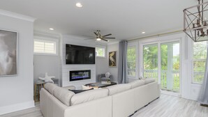 Una sala de estar moderna con un sofá modular grande, un televisor de pantalla plana y un ventilador de techo.