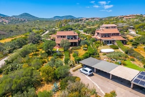 A large house with a spacious driveway, a covered carport, and a solar panel array.