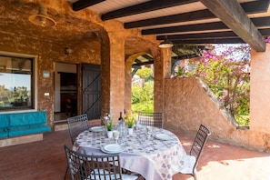 An outdoor patio with a round table set for dining, surrounded by chairs, and a bench.