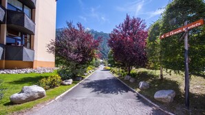 Camí cap a un edifici amb balcons, envoltat d'arbres i una muntanya al fons.