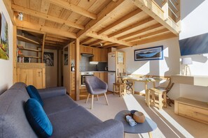 A cozy living area with a sofa, a dining table, and a kitchen in the background.