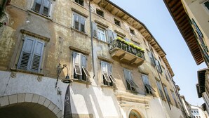 A historic building with multiple windows, some with shutters, and a balcony with plants. - Muri Di Arco, Arco, Italy (Arco)