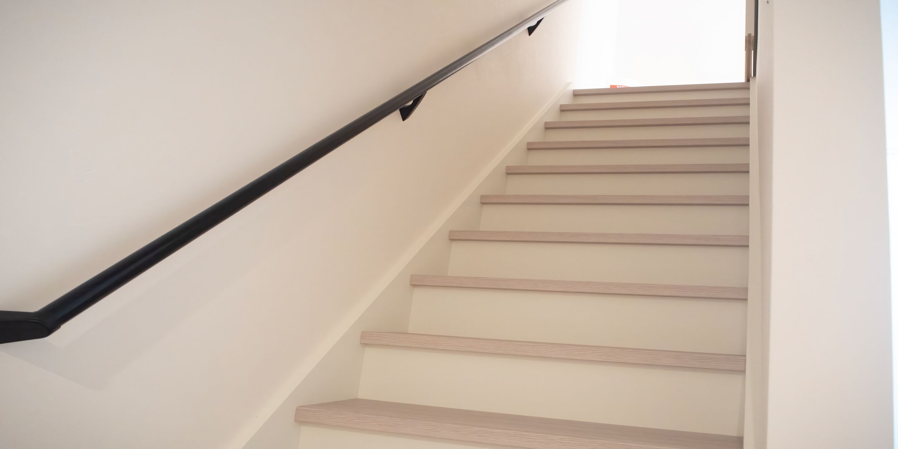 Eine Treppe mit Holzdielen und einem schwarzen Geländer.