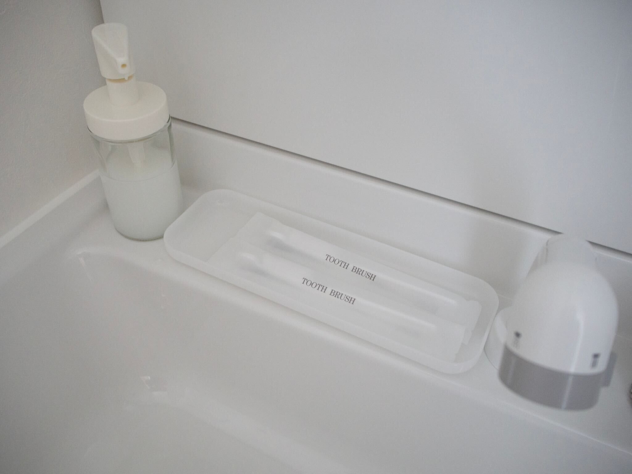 Un lavamanos blanco con un portalápices para cepillos de dientes y un dispensador de jabón.
