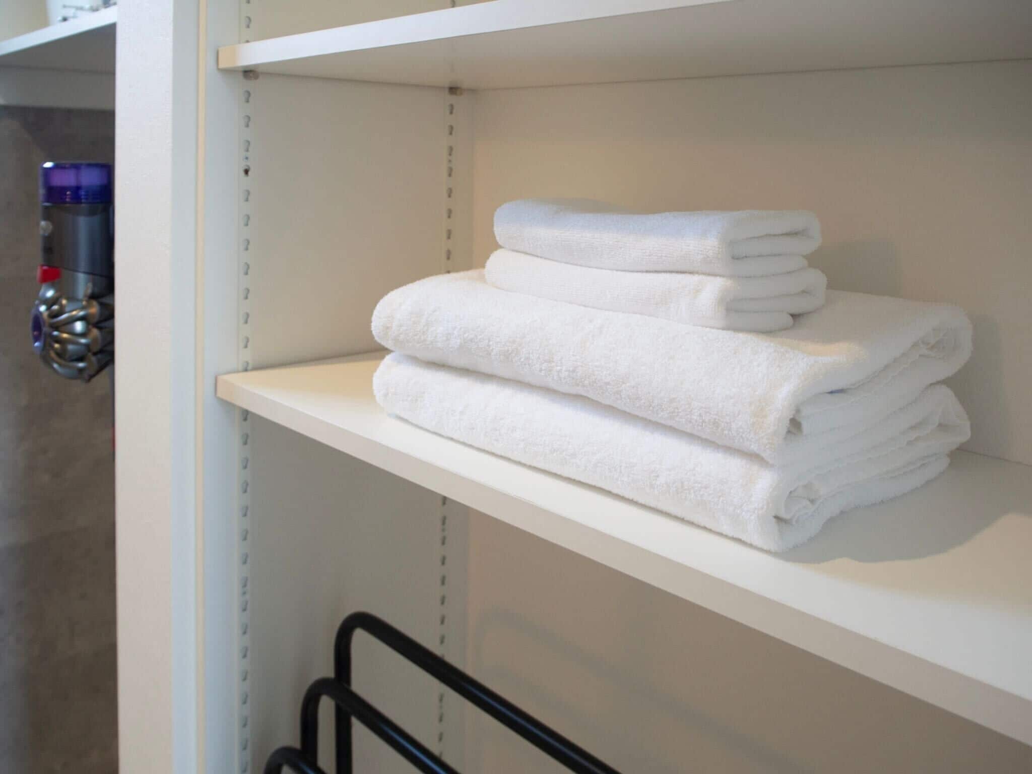 A white shelf with folded white towels.