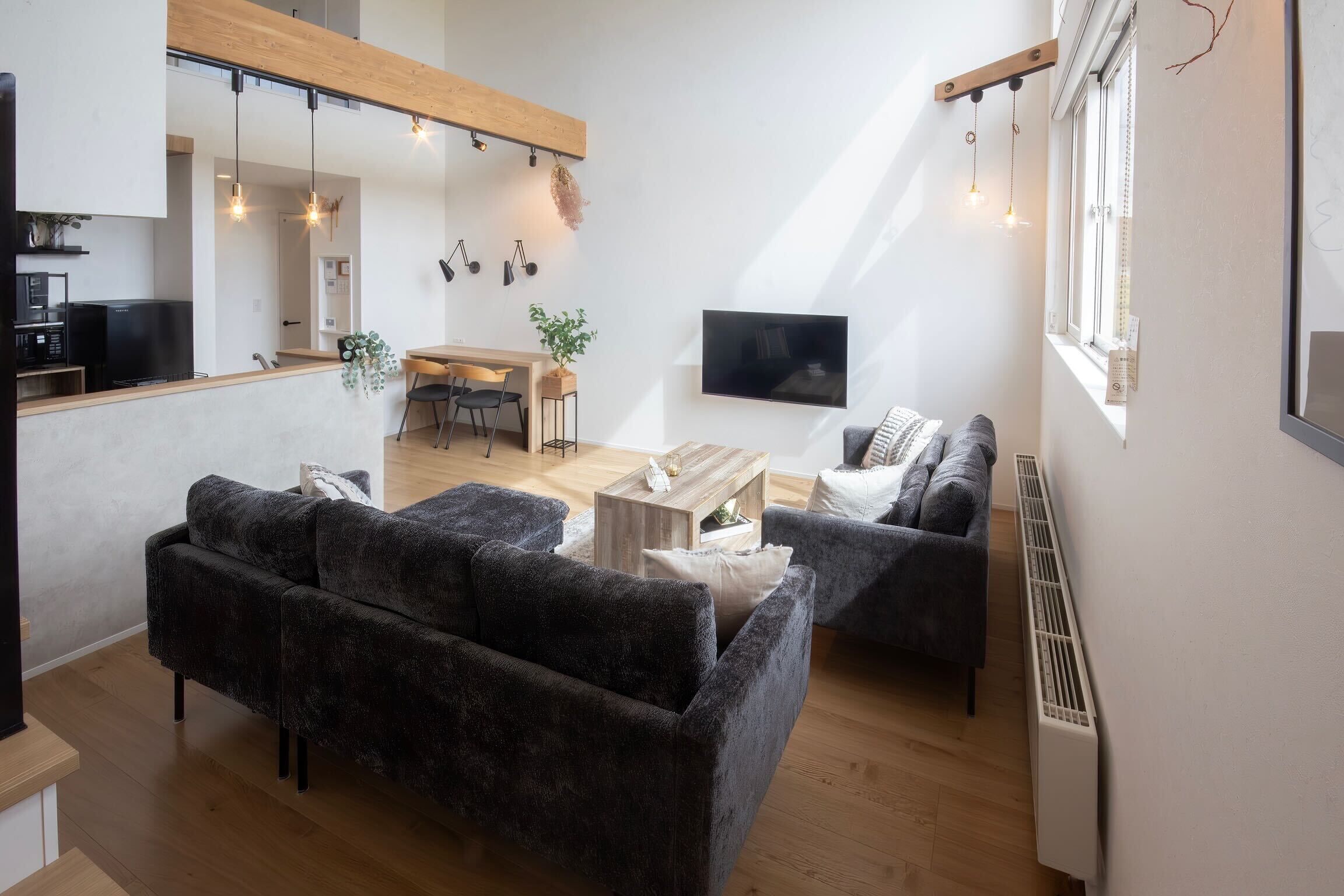 A modern living room with dark sofas, a wooden coffee table, and a TV mounted on the wall.