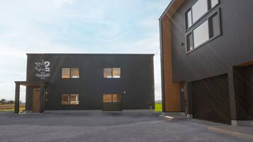 Un bâtiment moderne à la façade sombre, doté de nombreuses fenêtres et d’un espace de stationnement.