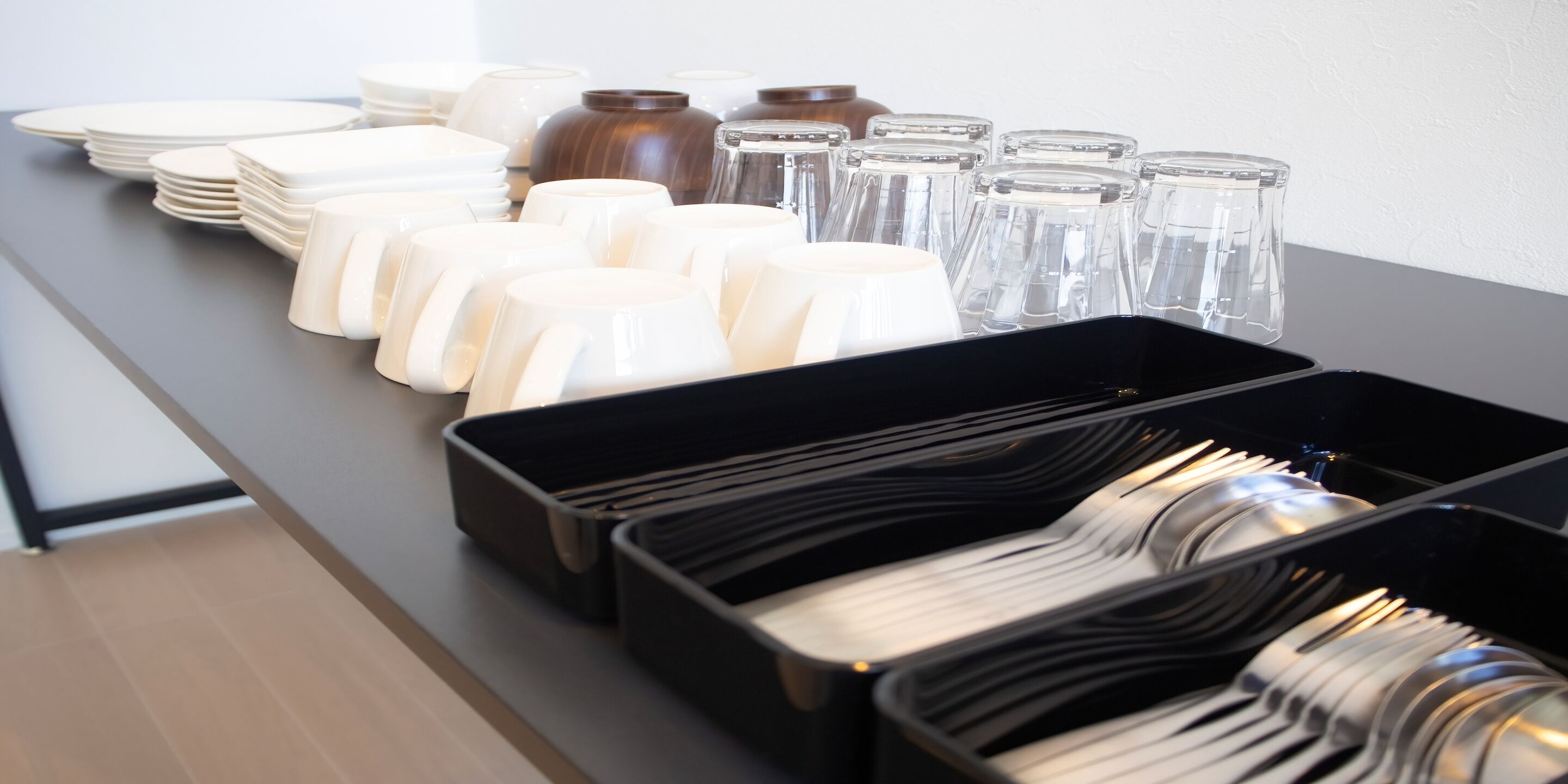 A table with neatly arranged plates, bowls, and glasses, suggesting a dining setup.