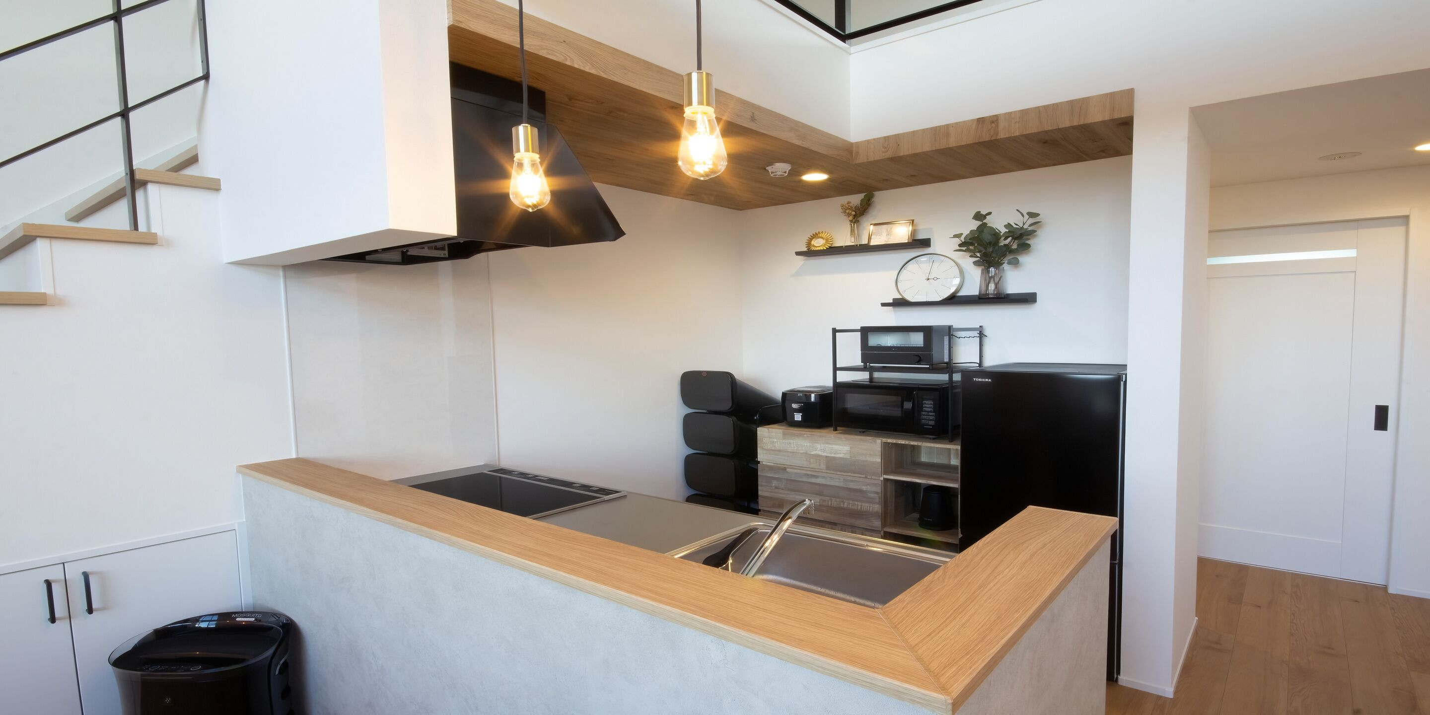 A modern kitchen with a central island, built-in appliances, and pendant lighting.