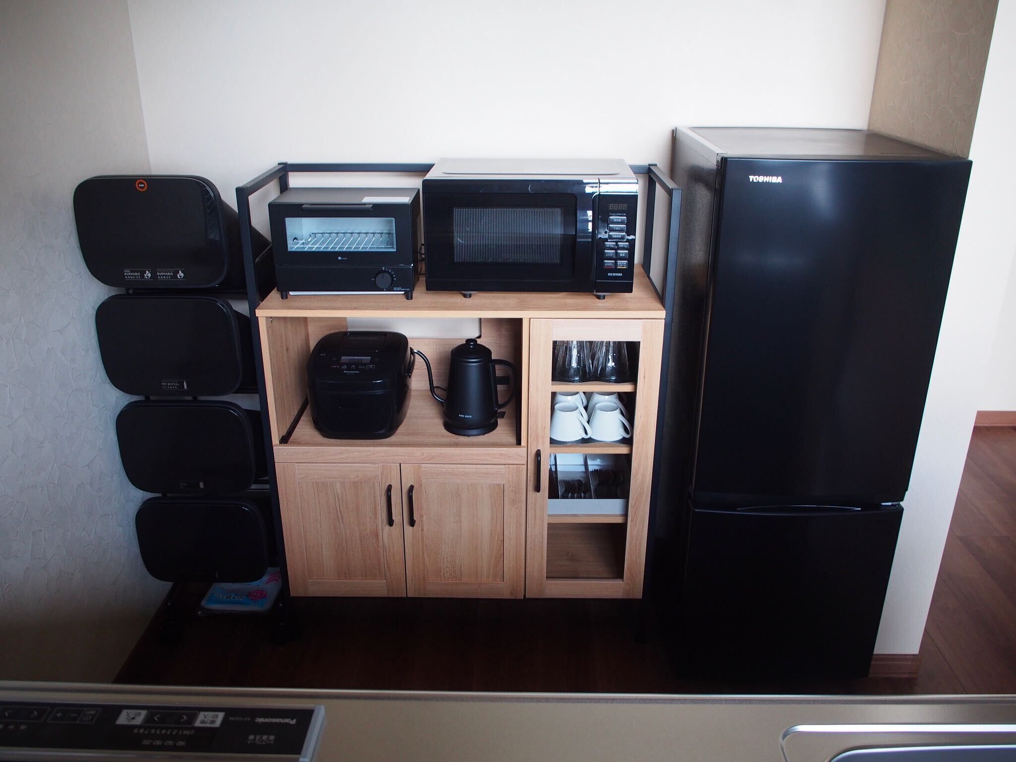 A compact kitchen with a microwave, toaster, coffee maker, and a refrigerator.