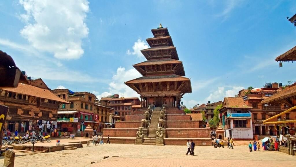 Une pagode traditionnelle à plusieurs niveaux, située sur une place animée et entourée d’immeubles.