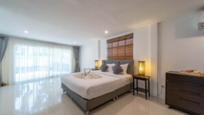 Una habitación de hotel moderna con una cama grande, mesitas de noche, un aparador y vistas a través de cortinas translúcidas.