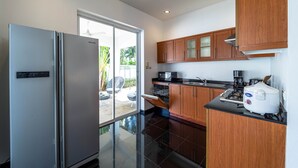 Una cocina moderna con refrigerador de acero inoxidable, armarios de madera y una cafetera.