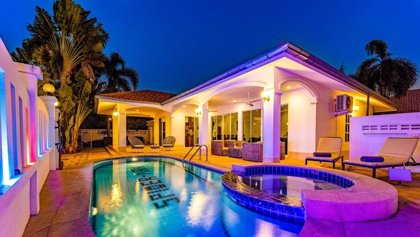 Una piscina con hidromasaje, rodeada de sillas de descanso y un patio techado.