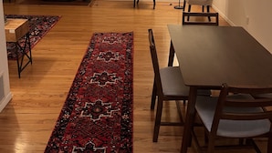 Un salon spacieux avec une cheminée, une table à manger avec des chaises, une grande moquette et un luminaire suspendu moderne.
