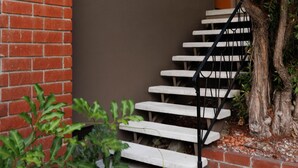 Un escalier avec des marches blanches et des rampes noires, menant à un mur brun.