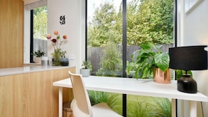 Una cocina moderna con encimera blanca, un armario de madera y una ventana con vistas a zonas verdes.